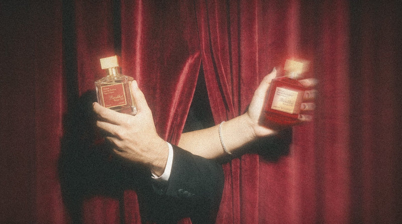 Barakkat Rouge 540 eau de parfum and extrait held out through a red velvet curtain